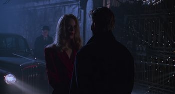 Movie still from “Batman Forever” (1995), directed by Joel Schumacher – A man and a woman are standing in a dark room; Medium shot, Over the shoulder angle