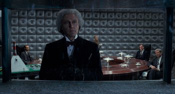 Movie still from “Batman Returns” (1992), directed by Tim Burton – A man in a tuxedo standing in front of a table; Medium shot, Low angle