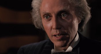 Movie still from “Batman Returns” (1992), directed by Tim Burton – An older man with a white hair and a beard; Close Up shot, Over the shoulder angle
