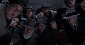 Movie still from “Batman Returns” (1992), directed by Tim Burton – A group of men and women wearing hats and ties; Medium shot, Overhead angle