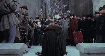 Movie still from “Batman Returns” (1992), directed by Tim Burton – A group of people standing in a circle with hats on; Wide shot, High angle