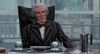 Movie still from “Batman Returns” (1992), directed by Tim Burton – An older man sitting at a table in a suit; Medium shot, Over the shoulder angle