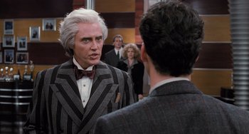 Movie still from “Batman Returns” (1992), directed by Tim Burton – A man in a suit and bow tie talking to another man in a suit and bow tie; Medium shot, Over the shoulder angle