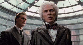 Movie still from “Batman Returns” (1992), directed by Tim Burton – Two men in suits and ties standing next to each other in front of a building; Close Up shot, Low angle