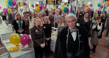 Movie still from “Batman Returns” (1992), directed by Tim Burton – A group of people standing in a room with balloons in the background; Medium shot, High angle