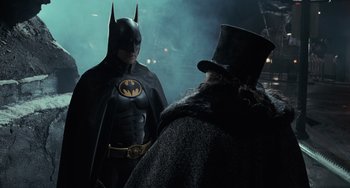Movie still from “Batman Returns” (1992), directed by Tim Burton – A man in a batman costume and a man in a top hat; Medium shot, Over the shoulder angle