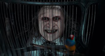 Movie still from “Batman Returns” (1992), directed by Tim Burton – A person in a cage with a bird; Close Up shot, Low angle