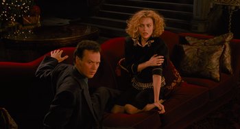 Movie still from “Batman Returns” (1992), directed by Tim Burton – A man and a woman sitting on a red couch; Medium shot, High angle