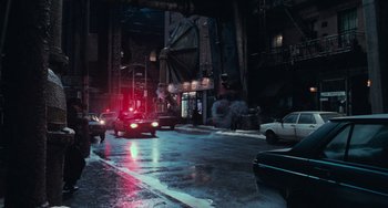 Movie still from “Batman Returns” (1992), directed by Tim Burton – Cars are driving down a wet street at night; Extreme Wide shot, High angle