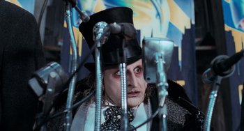 Movie still from “Batman Returns” (1992), directed by Tim Burton – A man in a top hat and a microphone stand with microphones; Close Up shot, Low angle