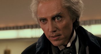 Movie still from “Batman Returns” (1992), directed by Tim Burton – A person wearing a suit and tie; Close Up shot, Low angle