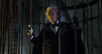Movie still from “Batman Returns” (1992), directed by Tim Burton – A man in a black suit standing behind bars; Medium shot, Low angle