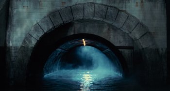 Movie still from “Batman Returns” (1992), directed by Tim Burton – A tunnel that has water coming out of it; Extreme Wide shot, High angle