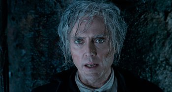 Movie still from “Batman Returns” (1992), directed by Tim Burton – A person wearing a suit and tie; Close Up shot, Low angle