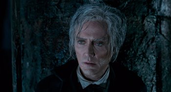 Movie still from “Batman Returns” (1992), directed by Tim Burton – A person wearing a suit and tie; Close Up shot, Low angle