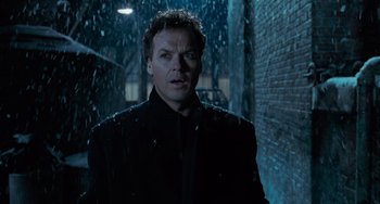 Movie still from “Batman Returns” (1992), directed by Tim Burton – A man standing in the rain in front of a brick wall; Close Up shot, Low angle