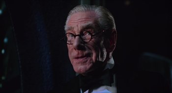 Movie still from “Batman & Robin” (1997), directed by Joel Schumacher – An older man wearing a bow tie and glasses; Close Up shot, Low angle