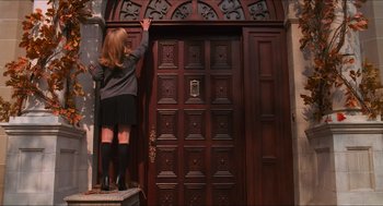 Movie still from “Batman & Robin” (1997), directed by Joel Schumacher – A woman standing in front of a wooden door; Wide shot, Low angle