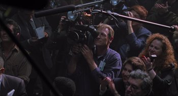 Movie still from “Batman & Robin” (1997), directed by Joel Schumacher – A man holding a video camera in front of a group of onlookers; Medium shot, High angle