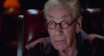 Movie still from “Batman & Robin” (1997), directed by Joel Schumacher – An old man with glasses sitting in a chair; Close Up shot, Low angle
