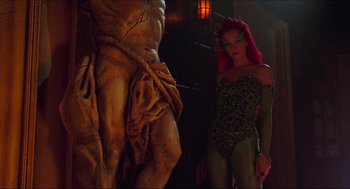 Movie still from “Batman & Robin” (1997), directed by Joel Schumacher – A woman dressed as poison ivy standing next to a statue; Medium shot, Low angle