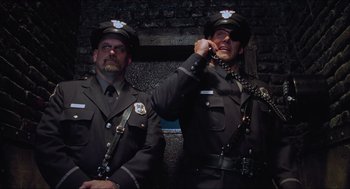 Movie still from “Batman & Robin” (1997), directed by Joel Schumacher – Two men in police uniforms are standing next to each other; Medium shot, Low angle