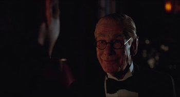 Movie still from “Batman & Robin” (1997), directed by Joel Schumacher – An old man wearing a bow tie in a dark room; Close Up shot, Over the shoulder angle