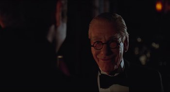 Movie still from “Batman & Robin” (1997), directed by Joel Schumacher – An old man wearing a bow tie in a dark room; Close Up shot, Over the shoulder angle