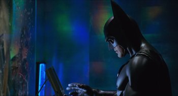 Movie still from “Batman & Robin” (1997), directed by Joel Schumacher – A person in a batman costume using a laptop; Medium shot, Low angle