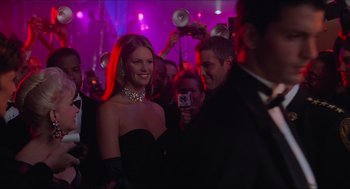 Movie still from “Batman & Robin” (1997), directed by Joel Schumacher – A woman in a black dress holding up a camera; Medium shot, Over the shoulder angle