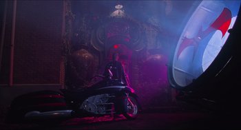 Movie still from “Batman & Robin” (1997), directed by Joel Schumacher – A person sitting on a motorcycle in a dark room; Wide shot, Low angle