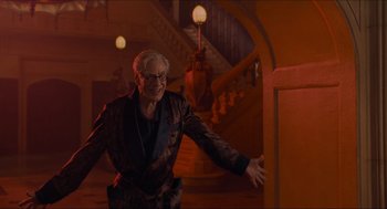 Movie still from “Batman & Robin” (1997), directed by Joel Schumacher – An older man in a suit and glasses is walking down the stairs; Medium shot, Low angle