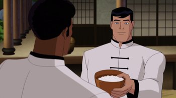 Movie still from “Batman: Soul of the Dragon” (2021), directed by Sam Liu – A man holding a bowl of rice in front of another man; Medium shot, Over the shoulder angle