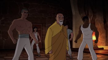 Movie still from “Batman: Soul of the Dragon” (2021), directed by Sam Liu – A group of men standing around a man in a yellow robe; Medium shot, Over the shoulder angle
