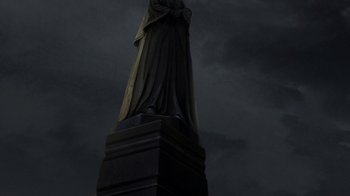 Movie still from “Batman: The Doom That Came to Gotham” (2023), directed by Sam Liu – A statue of a person in a dark sky; Extreme Wide shot, Low angle