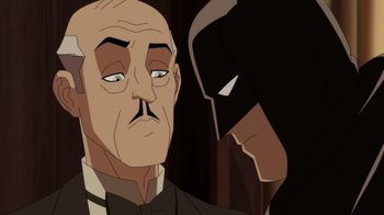 Movie still from “Batman: The Doom That Came to Gotham” (2023), directed by Sam Liu – A man in a suit and tie next to a batman mask; Close Up shot, Over the shoulder angle