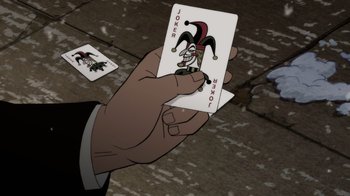 Movie still from “Batman: The Long Halloween” (2021), directed by Chris Palmer – A hand is holding a joker playing card; Extreme Close Up shot, High angle