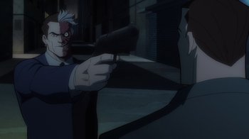 Movie still from “Batman: The Long Halloween” (2021), directed by Chris Palmer – A man holding a gun pointed at another man in a suit; Close Up shot, Over the shoulder angle