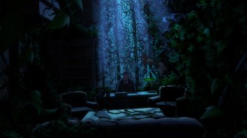 Movie still from “Batman: The Long Halloween, Part Two” (2021), directed by Chris Palmer – A man sitting at a table in a dark room; Extreme Wide shot, Low angle