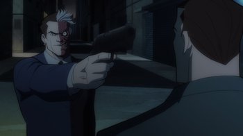 Movie still from “Batman: The Long Halloween, Part Two” (2021), directed by Chris Palmer – A man holding a gun pointed at another man in a suit; Close Up shot, Over the shoulder angle