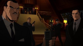 Movie still from “Batman: The Long Halloween, Part Two” (2021), directed by Chris Palmer – A group of men standing next to each other in front of a staircase; Medium shot, Over the shoulder angle