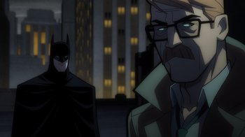 Movie still from “Batman: The Long Halloween, Part Two” (2021), directed by Chris Palmer – A cartoon of a man and a batman standing next to each other in front of some buildings; Close Up shot, Over the shoulder angle