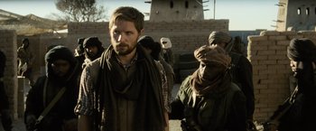 Movie still from “Batman v Superman: Dawn of Justice” (2016), directed by Zack Snyder – A group of men standing next to each other on a dirt road; Medium shot, Over the shoulder angle