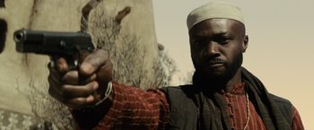 Movie still from “Batman v Superman: Dawn of Justice” (2016), directed by Zack Snyder – A man in a white hat is holding his hands in chains; Close Up shot, Low angle