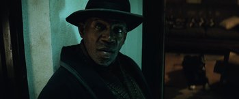 Movie still from “Batman v Superman: Dawn of Justice” (2016), directed by Zack Snyder – A man wearing a hat is looking at the camera; Close Up shot, Low angle