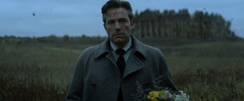 Movie still from “Batman v Superman: Dawn of Justice” (2016), directed by Zack Snyder – A man in a suit and tie holding flowers; Close Up shot, Low angle