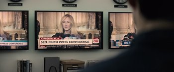 Movie still from “Batman v Superman: Dawn of Justice” (2016), directed by Zack Snyder – A tv screen with a bunch of people talking on it; Close Up shot, Over the shoulder angle