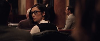 Movie still from “Batman v Superman: Dawn of Justice” (2016), directed by Zack Snyder – A woman with glasses sitting in a courtroom; Close Up shot, Over the shoulder angle