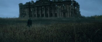 Movie still from “Batman v Superman: Dawn of Justice” (2016), directed by Zack Snyder – A person standing in a field near a building; Extreme Wide shot, Low angle