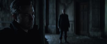 Movie still from “Batman v Superman: Dawn of Justice” (2016), directed by Zack Snyder – A man standing next to another man in a dark room; Close Up shot, Over the shoulder angle